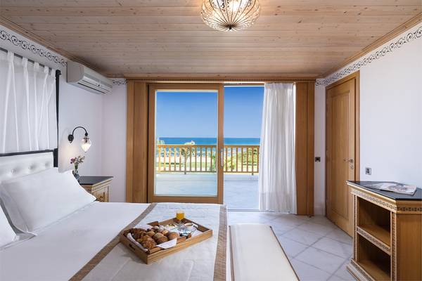 Zimmer im Mitsis Blue Domes Resort & Spa mit Frühstückstablett und Meerblick.