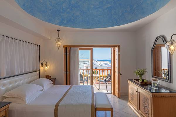 Schlafzimmer im Mitsis Blue Domes Resort & Spa mit Balkon und Meerblick.