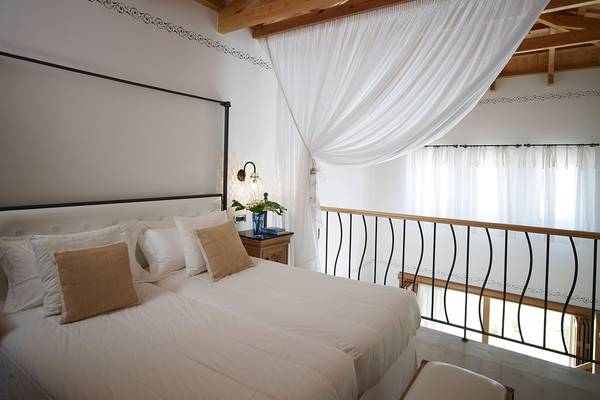 Schlafzimmer im Mitsis Blue Domes Resort mit weißem Bett, Dekor und Balkon