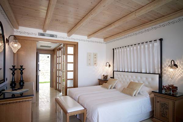 Schlafzimmer im Mitsis Blue Domes Resort & Spa mit Holzdecke, weißen Wänden und zwei Betten.