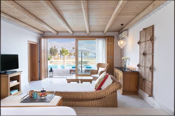 Wohnbereich des Mitsis Blue Domes Resort & Spa mit Terrasse und Poolblick