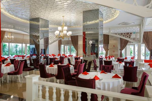 Innenbereich des Well Palace Side Hotels mit gemusterter Decke, Spiegeln und gedeckten Tischen.