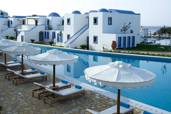 Poolbereich des Mitsis Blue Domes Resorts mit weißen Liegestühlen und Sonnenschirmen