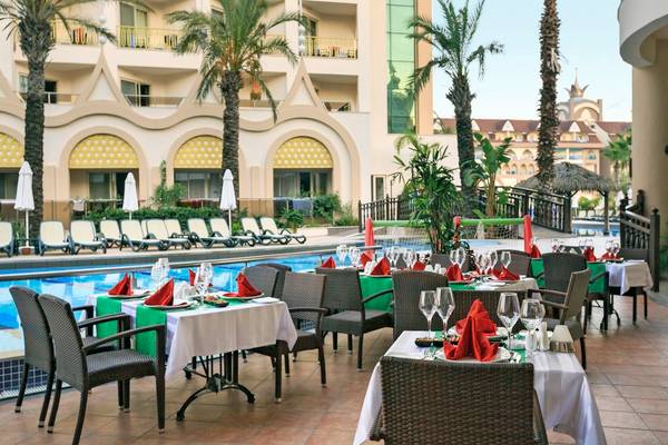 Außenbereich des Well Palace Side Hotels mit Tisch und Stuhl für Gäste, neben dem Pool.