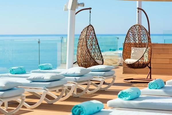 Außenbereich des Iberostar Selection Playa de Palma Hotels mit Sonnenliegen und Hängesesseln mit Blick auf das Meer.