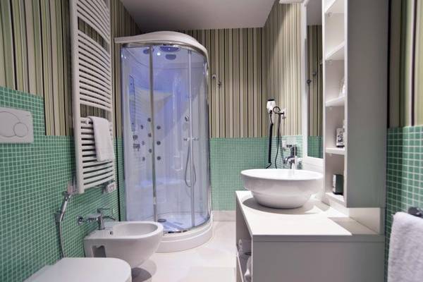 Badezimmer im Hotel Residence il Porto mit grünen Fliesen, Glasdusche und Waschbecken.
