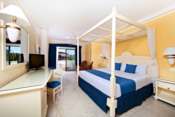 Suite-Zimmer im Bahia Principe Grand Tulum mit Himmelbett, Fernseher und Balkonzugang.