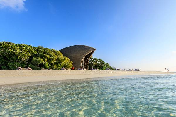 Strand und Gebäude des Dhigali Maldives Hotels an einem sonnigen Tag.