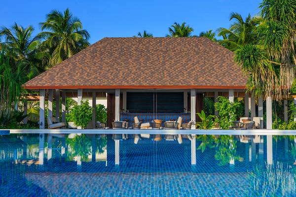 Außenbereich des Dhigali Maldives Hotels mit Swimmingpool und umgebenden Palmen.