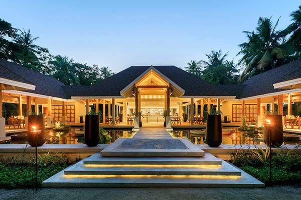 Außenansicht des Dhigali Maldives Hotels mit beleuchtetem Eingang und Wasserelementen