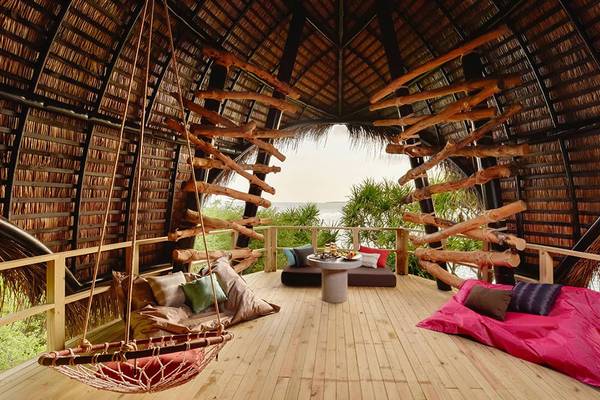 Innenansicht des Dhigali Maldives Hotels mit Holzbalkendecke und Blick aufs Meer.