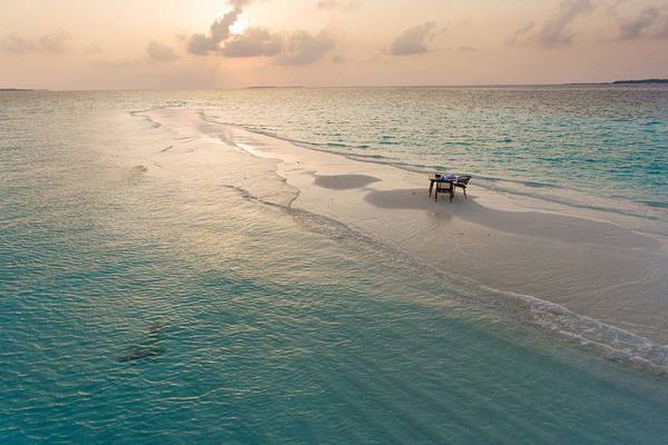 Luftaufnahme von Dhigali Maldives mit einem Tisch und Stühlen am Strand.