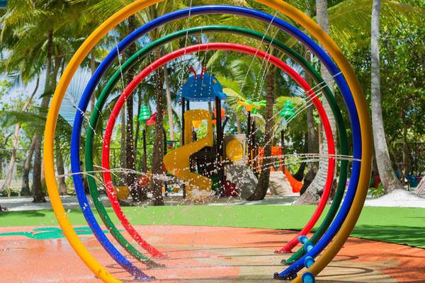 Spielplatz im Dhigali Maldives mit bunten Wasserspielkreisen und Palmen im Hintergrund.