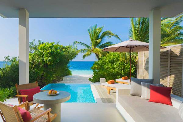 Terrasse des Dhigali Maldives Hotels mit Swimmingpool, Strand und Meer im Hintergrund