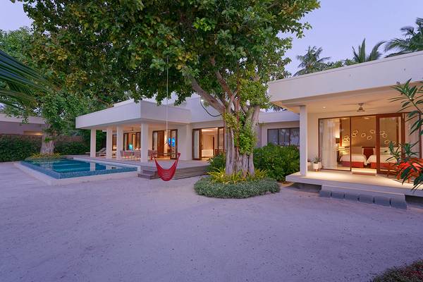 Außenansicht der Dhigali Maldives Villa mit Swimmingpool, Hängematte und modernem Design.
