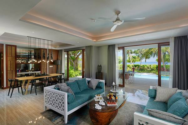 Wohnbereich im Dhigali Maldives Hotel mit Blick auf den Ozean und eine Terrasse.