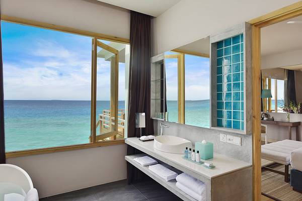 Badezimmer im Dhigali Maldives Hotel mit Aussicht auf das Meer.