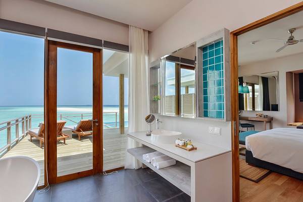 Innenansicht eines Hotelzimmers im Dhigali Maldives mit Blick auf das Meer und eine Terrasse.