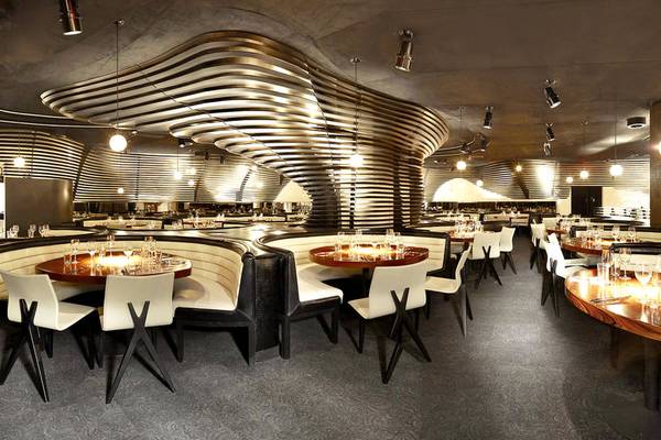 Innenraum des Restaurants Cosmopolitan of Las Vegas mit modernen Möbeln und geschwungenen Deckendesigns.