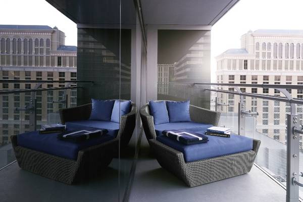Ein Hotelbalkon mit zwei blauen Rattan-Sitzmöbeln und Büchern darauf.