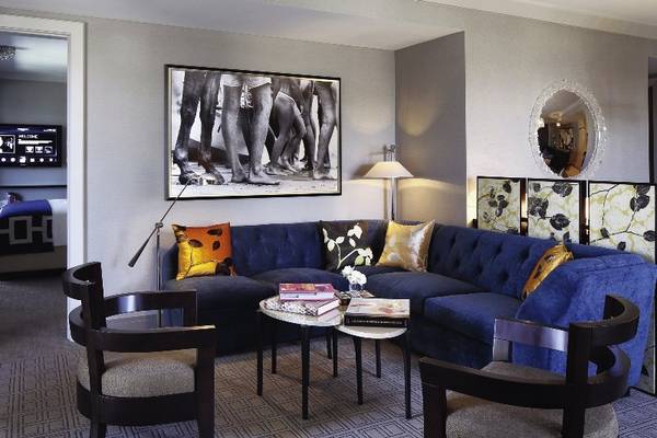 Hotelzimmer mit blauer Couch, Tisch, Kissen und Dekor.