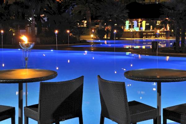 Außenpool mit brennenden Fackeln und Tischen im Sol Principe Hotel bei Nacht