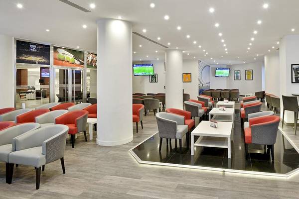Lounge-Bereich im Sol Principe Hotel mit vielen Stühlen, Tischen, Fernsehern und einer gefliesten Tanzfläche.