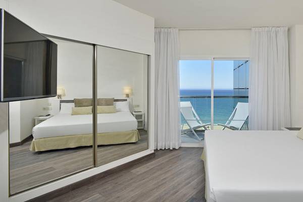 Innenansicht eines Hotelzimmers im Sol Principe Hotel mit Blick auf das Meer und zwei Sonnenliegen.