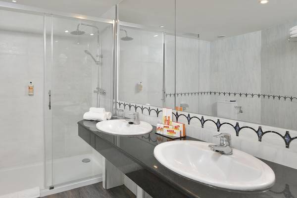 Das Badezimmer im Sol Principe Hotel mit einer Dusche, zwei Waschbecken und einem Spiegel.