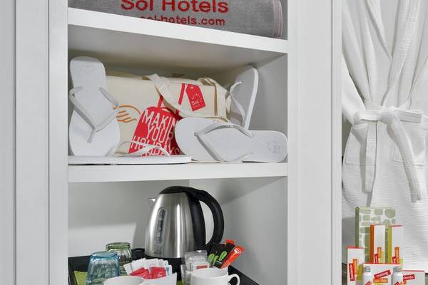 Ein Hotelzimmer des Sol Principe mit einem Schrank, Flip-Flops, einem Wasserkocher und weiteren Gegenständen.