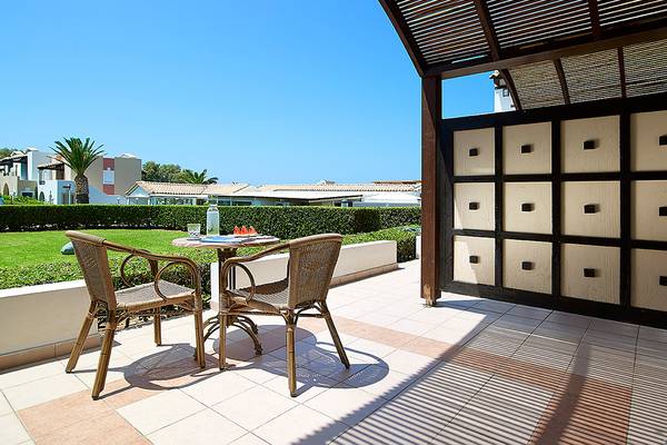 Terrasse mit zwei Stühlen und einem Tisch im Aldemar Knossos Royal Resort Hotel.