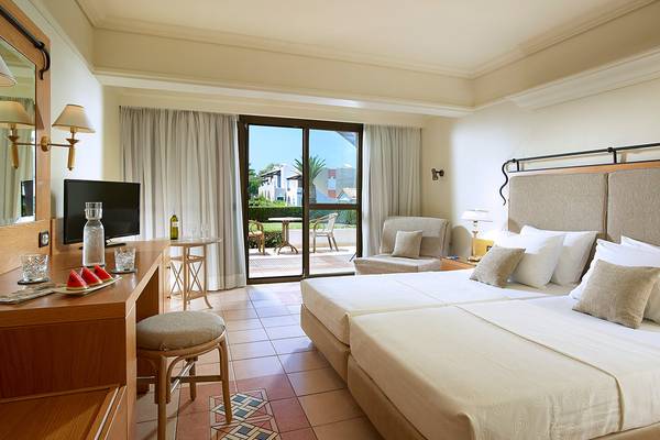 Doppelzimmer mit Terrasse im Aldemar Knossos Royal Resort, mit zwei Betten, Schreibtisch und Fernseher.