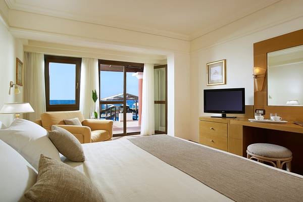 Ein modernes Hotelzimmer mit Meerblick, Fernseher, Schreibtisch und bequemen Möbeln im Aldemar Knossos Royal Resort.