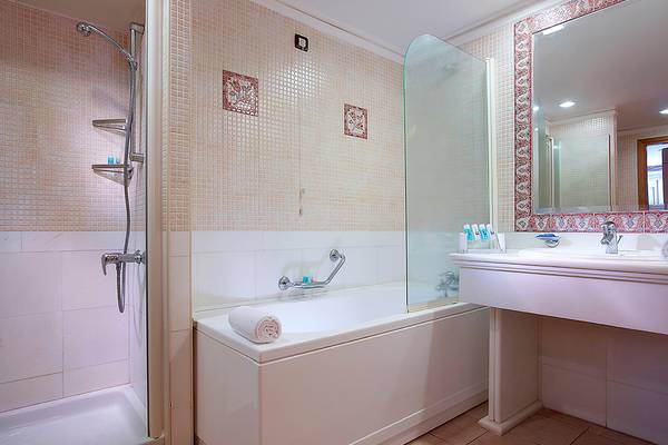 Badezimmer im Aldemar Knossos Royal Resort mit Badewanne, Dusche und Waschbecken.