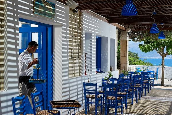 Mann vor einer blauen Tür im Hotel Aldemar Knossos Royal Resort mit Blick auf das Meer