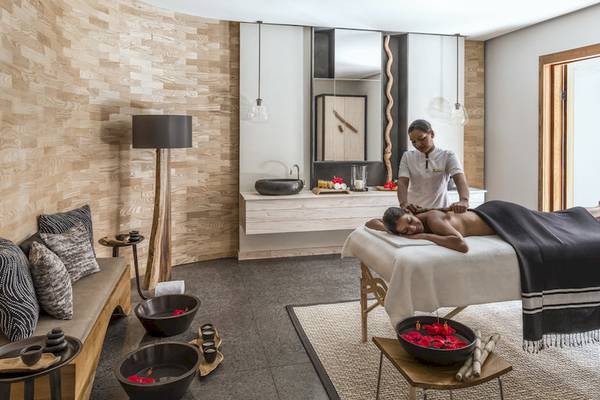 Massagebehandlung im Hotel Shangri-La Le Touessrok mit einem Kunden, der sich entspannt auf einem Massagebett befindet.