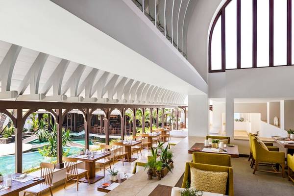 Innenbereich des Restaurants Shangri-La Le Touessrok mit Tischen, Stühlen und Blick auf den Pool.