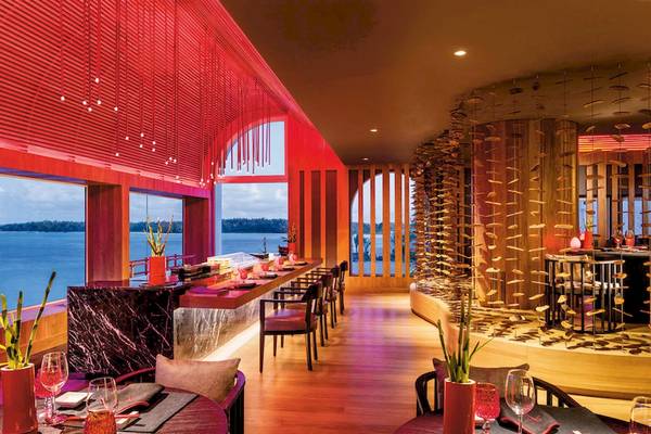 Innenansicht des Restaurants Shangri-La Le Touessrok mit Blick auf das Meer, rotes Dekor, Tische und Stühle.