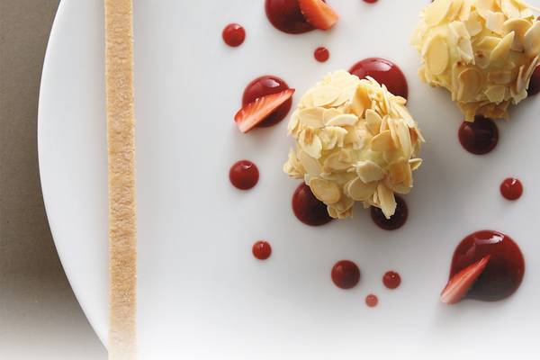 Mandel-Schoko-Kugel auf weissem Teller mit Erdbeeren und roter Glasur