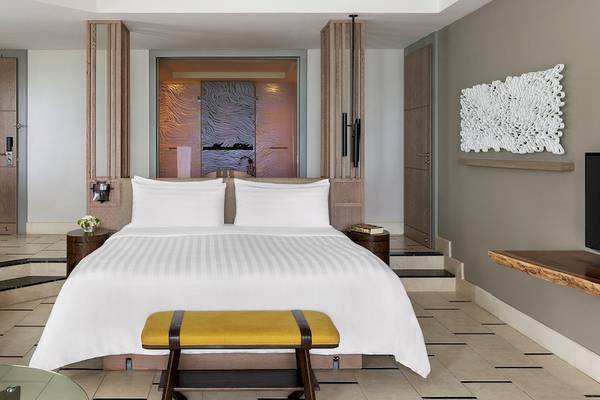 Luxus Schlafzimmer im Hotel Shangri-La Le Touessrok mit großem Bett, zwei Nachttischen und moderner Einrichtung.