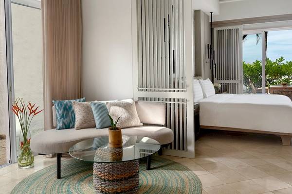 Hotelzimmer im Shangri-La Le Touessrok mit Bett, Sofa, Tisch und Aussicht auf den Ozean.