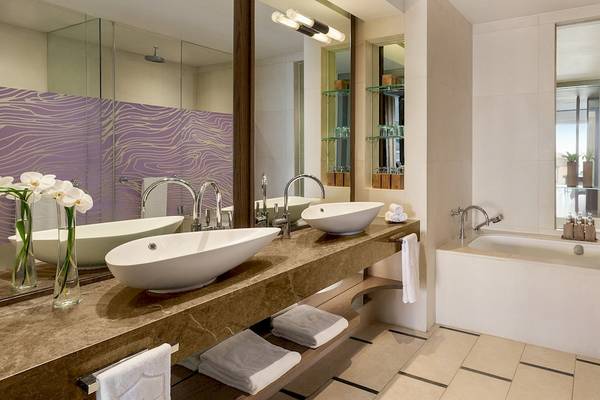 Ein modernes Badezimmer mit zwei Waschbecken, einer Badewanne und einem Spiegel im Shangri-La Le Touessrok Hotel.
