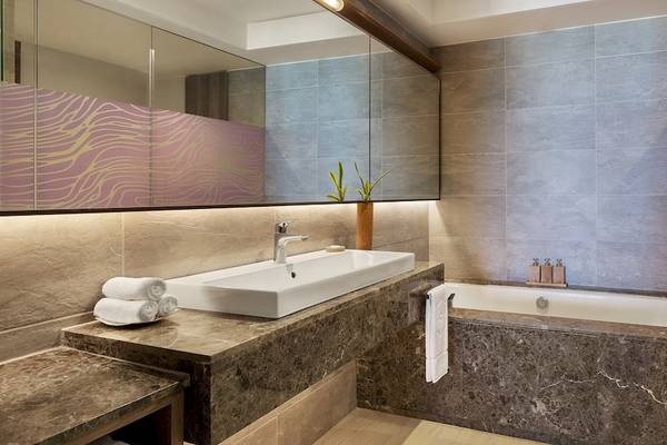 Badezimmer im Shangri-La Le Touessrok Hotel mit Badewanne, Waschbecken, Handtüchern und Spiegel.