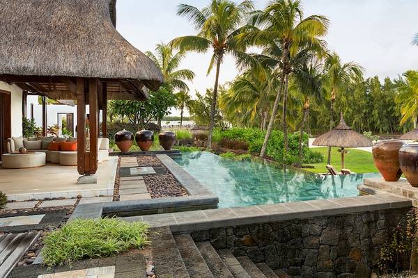 Außenbereich des Shangri-La Le Touessrok Hotels mit Pool, Palmen und Meer im Hintergrund.