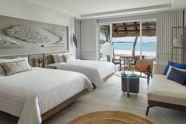 Zimmer im Shangri-La Le Touessrok Hotel mit zwei Betten und Aussicht auf den Strand.