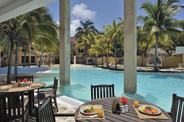 Außenbereich des Melia Las Americas Hotels mit Swimmingpool und Frühstückstischen.