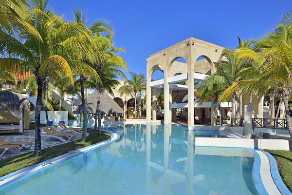 Außenpool im Melia Las Americas Hotel mit Palmen und Loungeliegen.