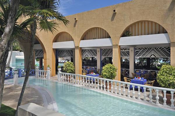 Außenpool und Restaurant des Melia Las Americas Hotels mit blauen Tischen und Stühle.