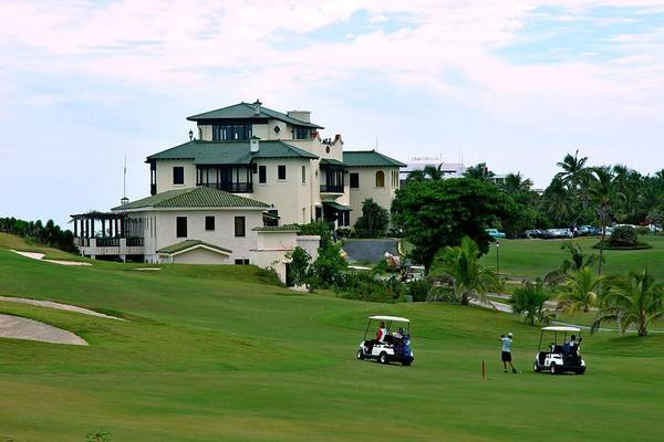 Golfplatz mit Golfwagen und Hotel Melia Las Americas im Hintergrund