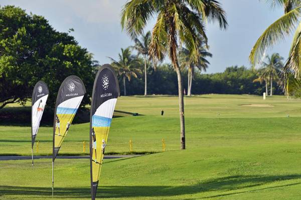 Golfplatz mit Palmen und Bannern vor dem Melia Las Americas Hotel.